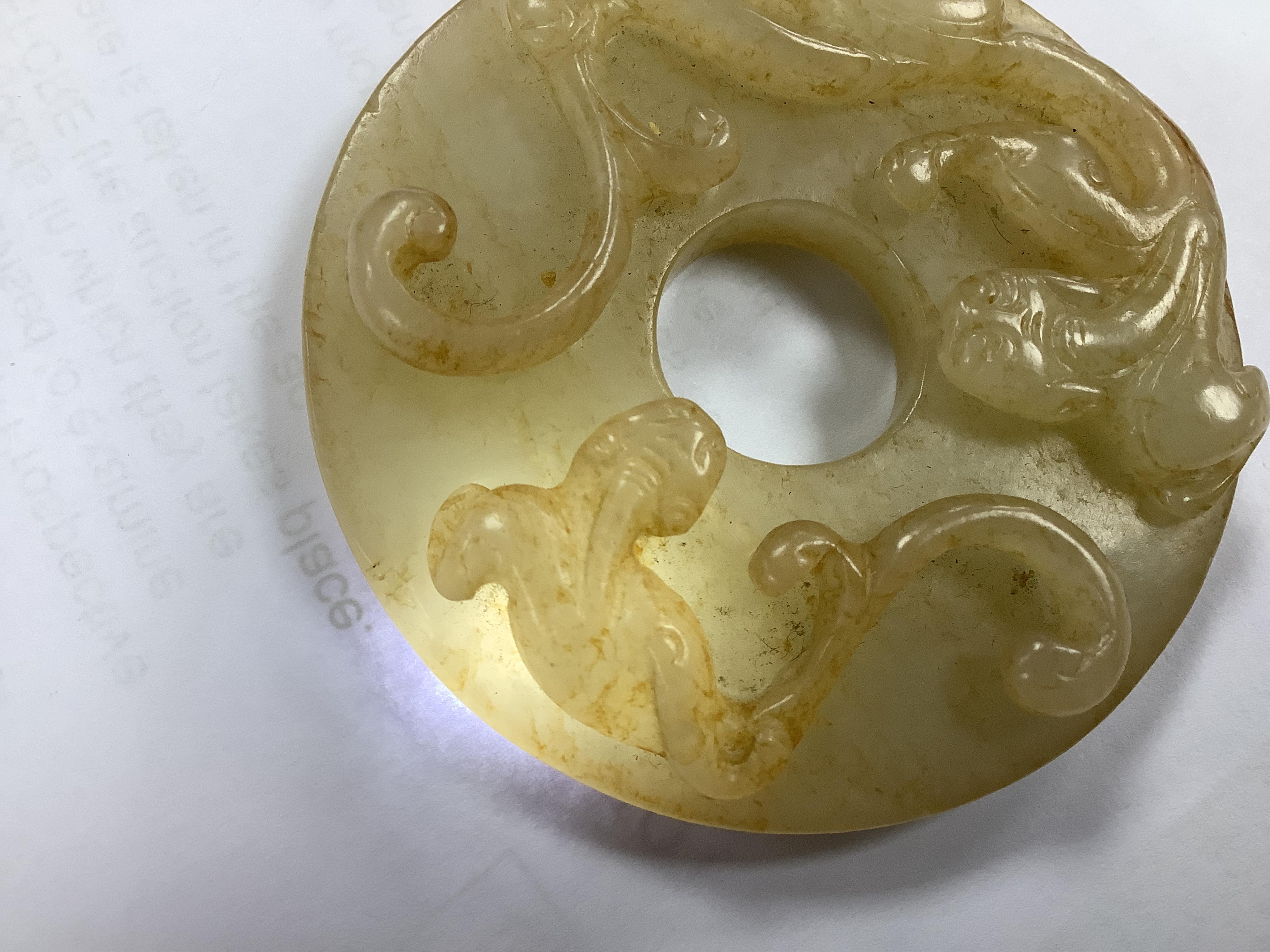 An 18th century Chinese mottled jade bi disc, decorated with two carved chilong, 5.8cm diameter